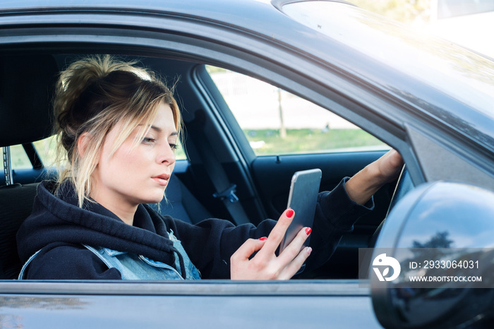 Girl driving car and texting on her smartphone