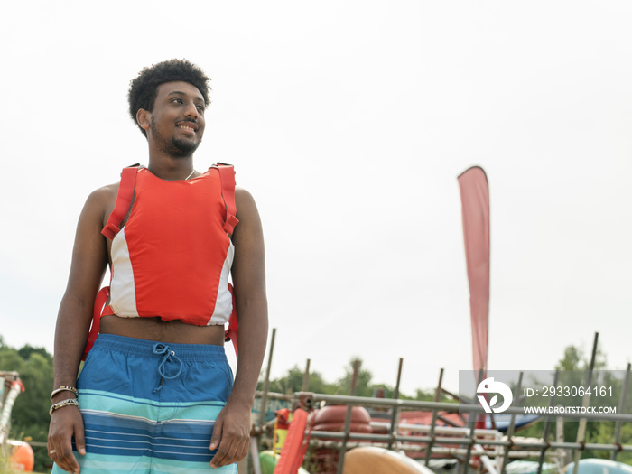 Portrait of young man wearing life jacket on beach