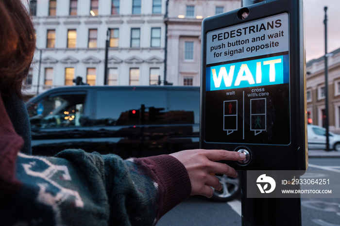 pushing a button of a signal traffic light at pedestrian crossing in London