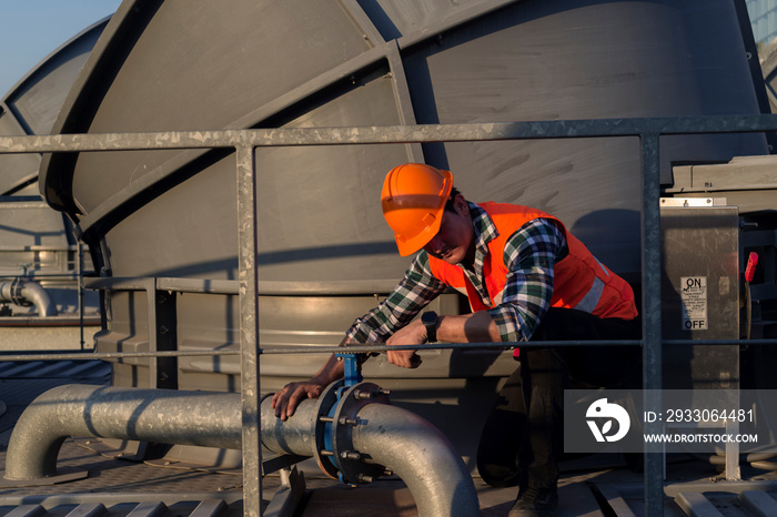 worker open valve of cooling tower on blue sky background.worker opening butterfly valve on top of cooling Tower. engineer check valve on cooling tower