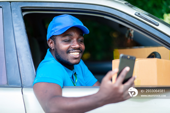 African delivery man looking smart phone in the car