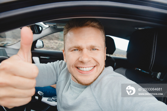 Happy man driver buyer car looking camera and taking selfie photo, beautiful smile. Concept preparing for road trip, auto rental