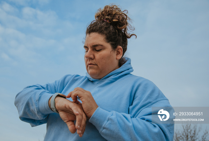 plus size woman looking at fitness tracker