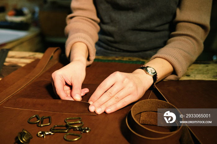 young brunette woman works in a bag making studio, cuts out details