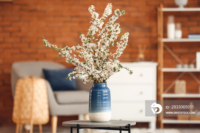 Vase with beautiful blossoming branches on table in room