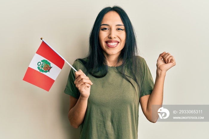 Young hispanic girl holding peru flag screaming proud, celebrating victory and success very excited with raised arm