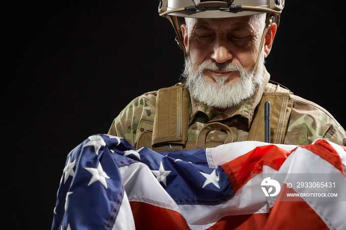 Veteran in military uniform holding american flag.