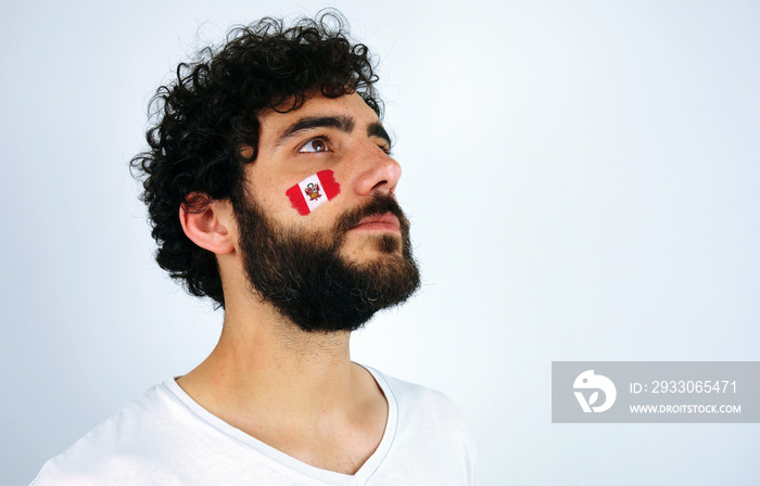 Sport fan head high and feeling proud when listening to the anthem of his country. Man with the flag of Peru makeup on his face and white t-shirt.