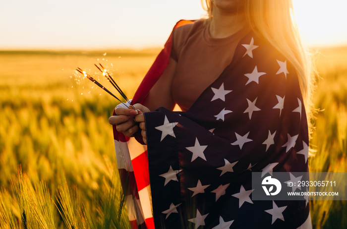 Girl holding bengal fire with American flag at sunset Celebrate Independence Day of America. 4h of July. Patriotic holiday