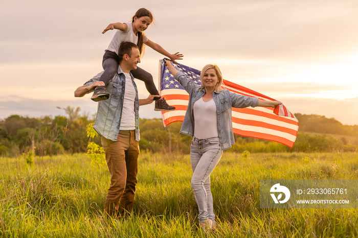 family holding up an American flag in a field.