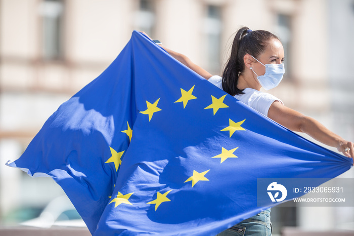 EU flag on a back of a woman wearing a face mack outdoors