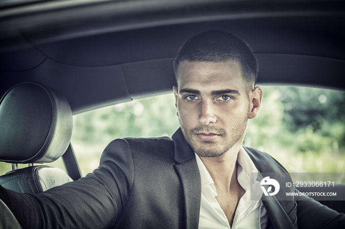 Handsome Young Man Driving a Car, wearing black jacket, hand on wheel