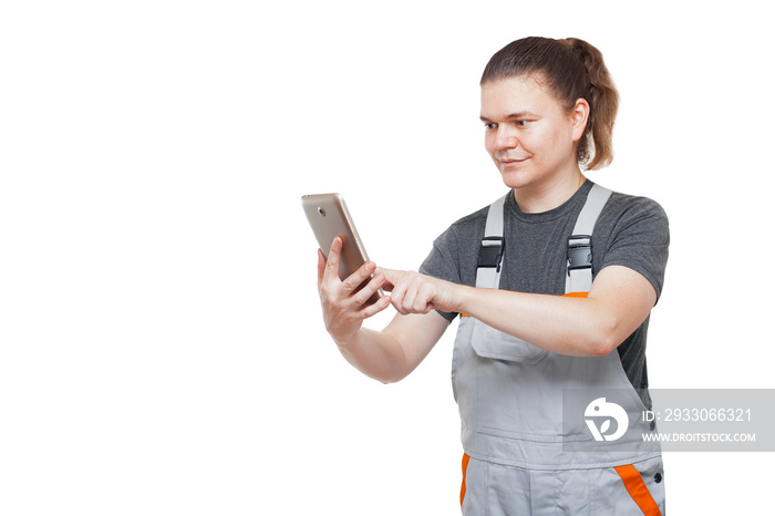 worker in gray uniform overalls holds a tablet mobile device for online service and purchases of goods, mechanic isolated on a white background.