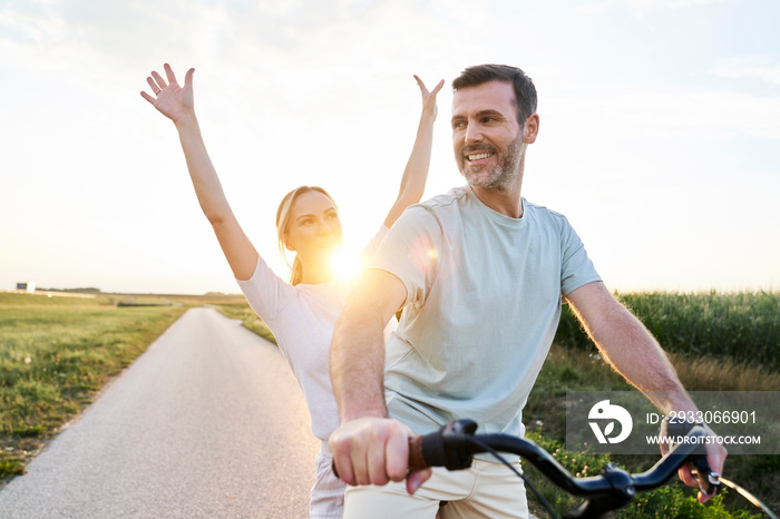 Playful caucasian couple having fun on a bike on village road