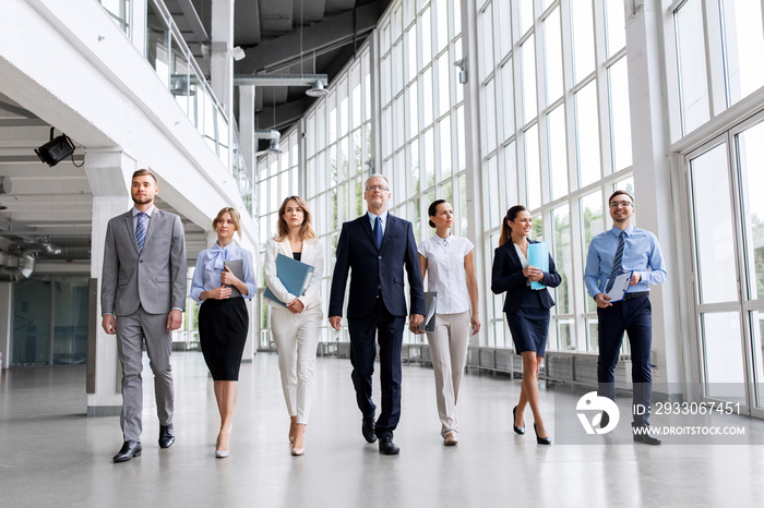 people, work and corporate concept - business team with folders walking along office building and talking