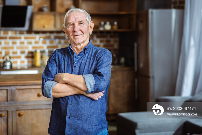 Positive elderly man standing in the kitchen