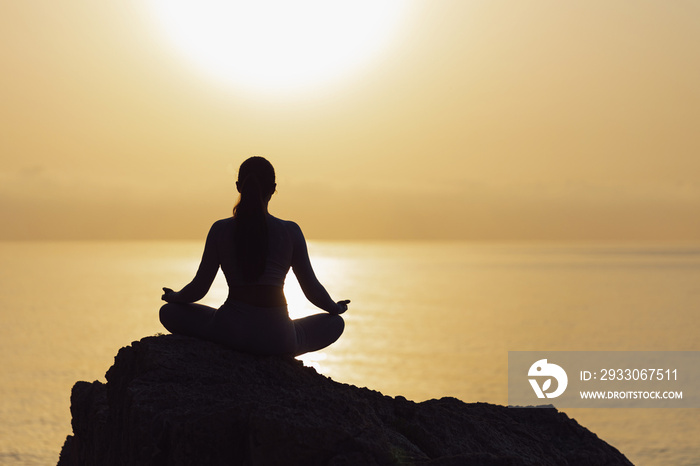 Serenity and yoga practicing at sunset, meditation. silhouette on sea background with sunrise