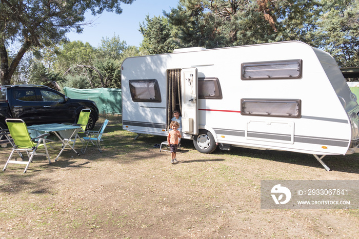 two Caucasian children play and spend alternative holidays in a caravan