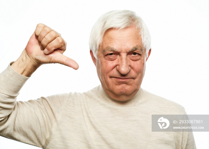 Emotion, old people and body language concept: Senior man standing over isolated white background looking unhappy and negative with thumbs down gesture.