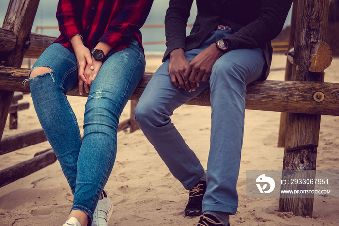 Couple in blue jeans relaxing on a beach.