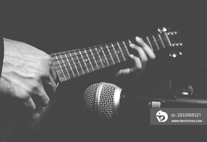 musician hands playing & recording acoustic guitar, isolated on black + BW film filter