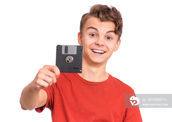 Portrait of confused teen boy with old Floppy Disk, isolated white background. Teenager with diskette in his hand. Surprised child with retro information storage.