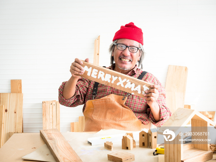 Portrait of an elderly male carpenter proudly standing in a workshop after completing his work preparing for the Christmas season.