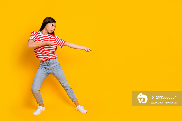 Full size profile portrait of confident concentrated girl look hands pull empty space isolated on yellow color background