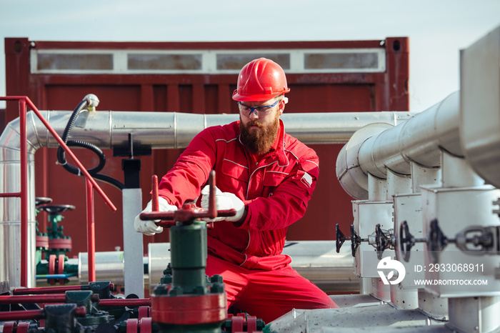 Oil worker turning valve on oil rig