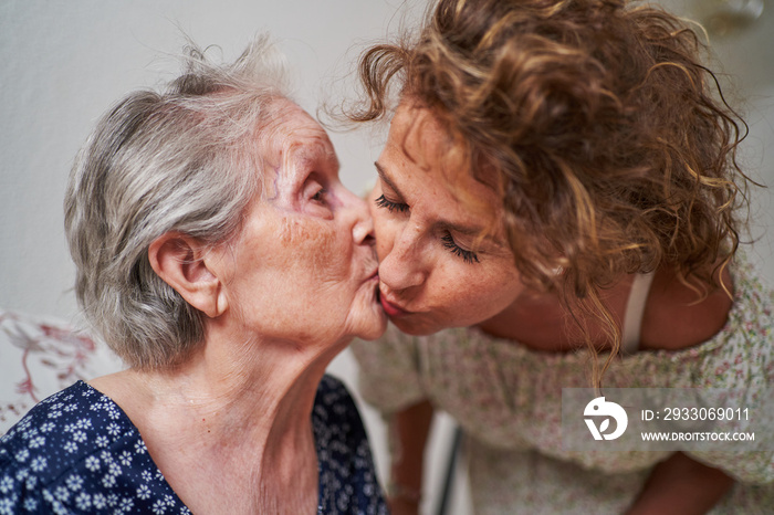 Woman receiving a kiss her 90 year old mother