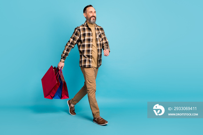 Full body photo of mature man go shopping hold bags isolated over blue color background