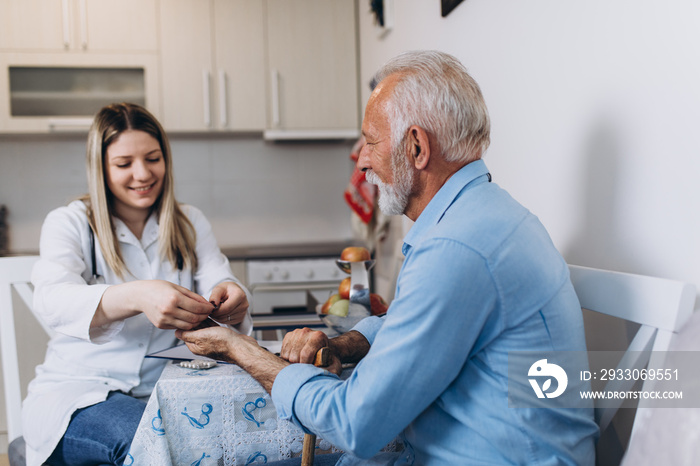 Young positive caregiver taking care of senior man in nursing home