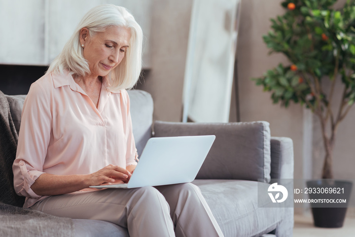 Nice aged woman using her laptop at home