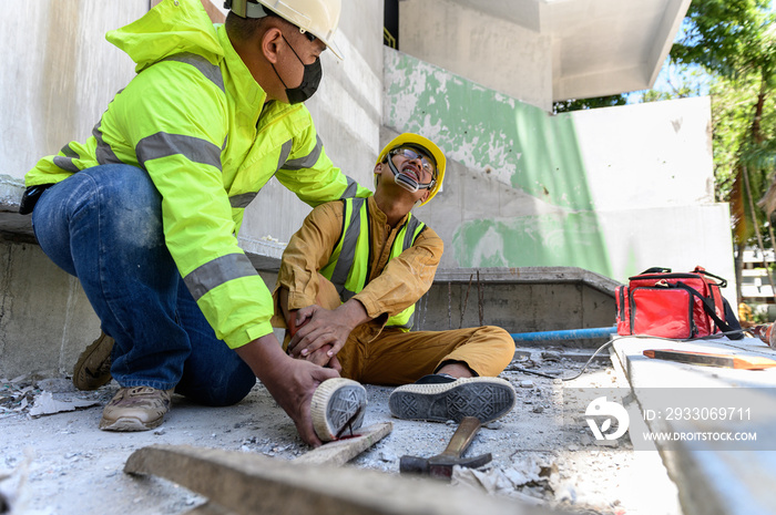 Builder worker has an accident at work. His feet stepped on nails embedded in wood old with foreman rushed in to take care. First aid and Safety in work concept.