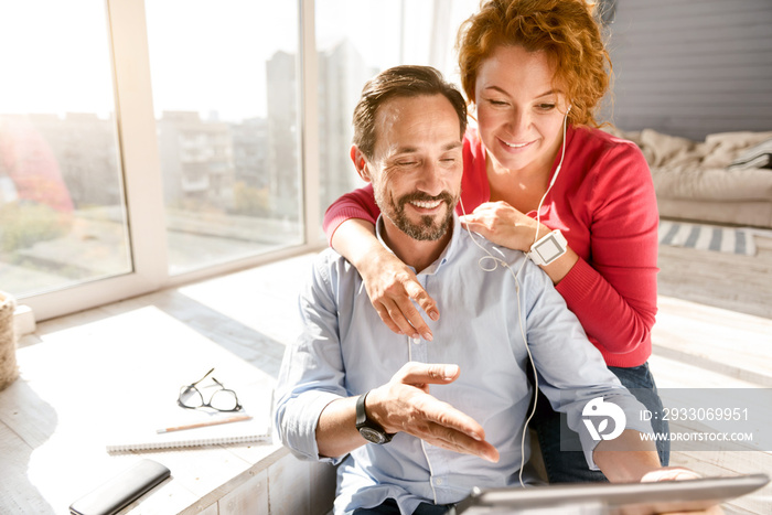 Happy middle aged couple using gadgets at home