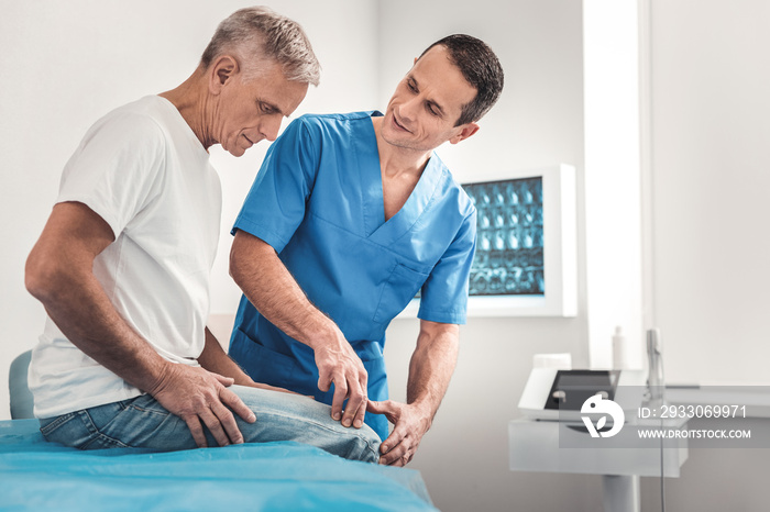 Chiropractor in blue uniform talking to his patient