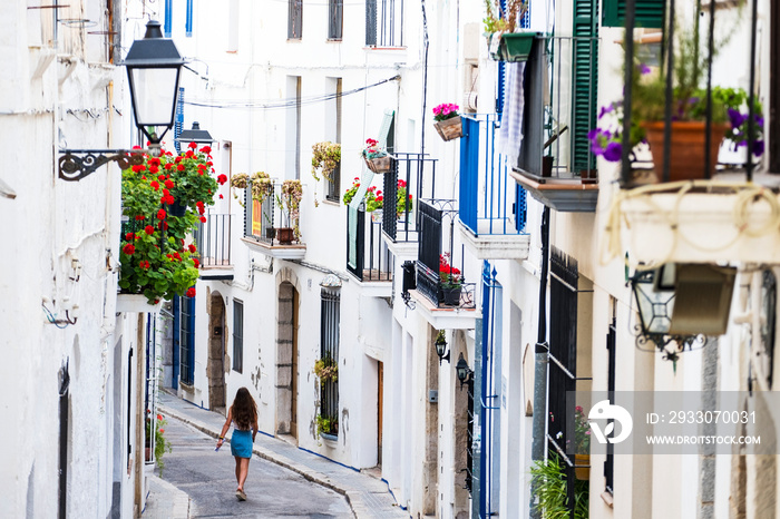 Street in the center of the city of Sitges with a young girl walking towards the beach, Spain