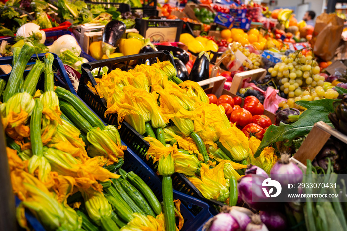 Yellow zucchini flowers and other fresh vegetables for sale on farmers market in Florence, Tuscany, Italy