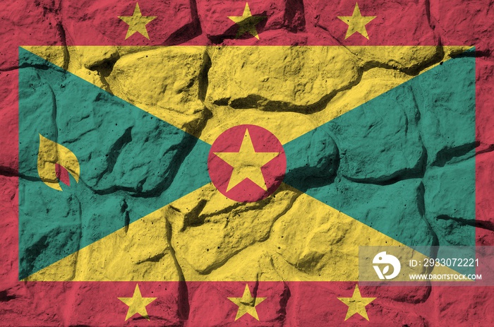 Grenada flag depicted in paint colors on old stone wall closeup. Textured banner on rock wall background