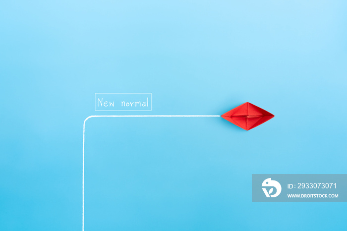 red paper ship in new direction on blue background, New normal concept, copy space