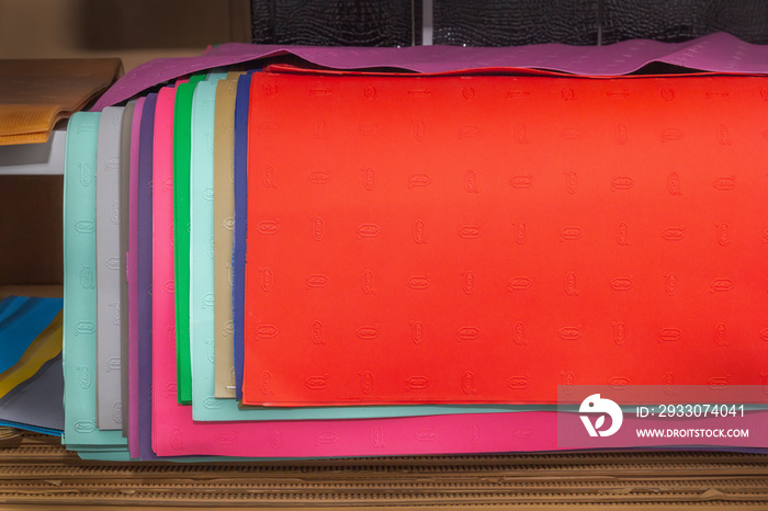 Multi-colored leather and rubber blanks for repairing and making shoes on the shelves of a shoemaker’s shop