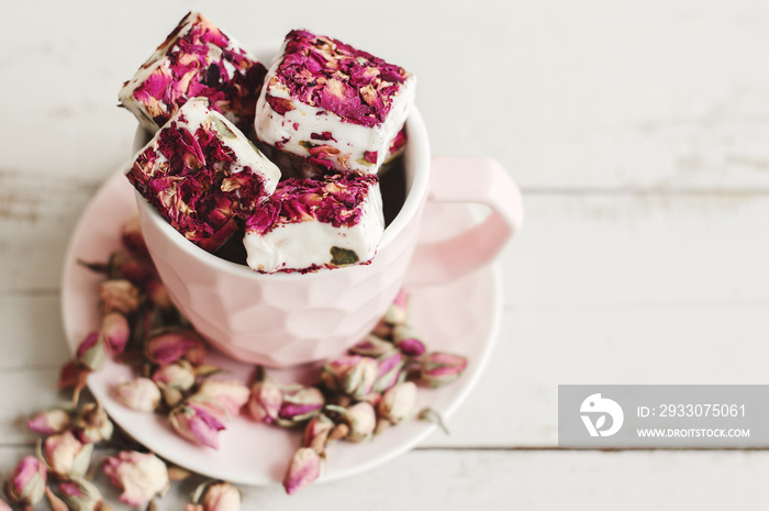 Pink coffee cup with nougat and dried rose buds. Turkish delight with petals. Lebanese sweets. Dessert with edible flowers