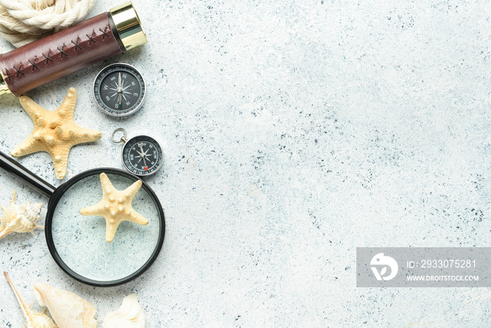 Magnifier, spyglass, compasses and starfishes on light background