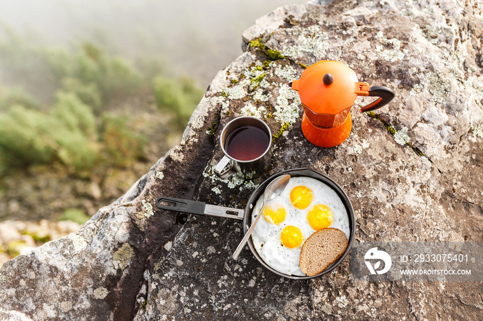 breakfast meal Fried eggs in pan and coffee geyser maker outdoors in mountains, camping food concept