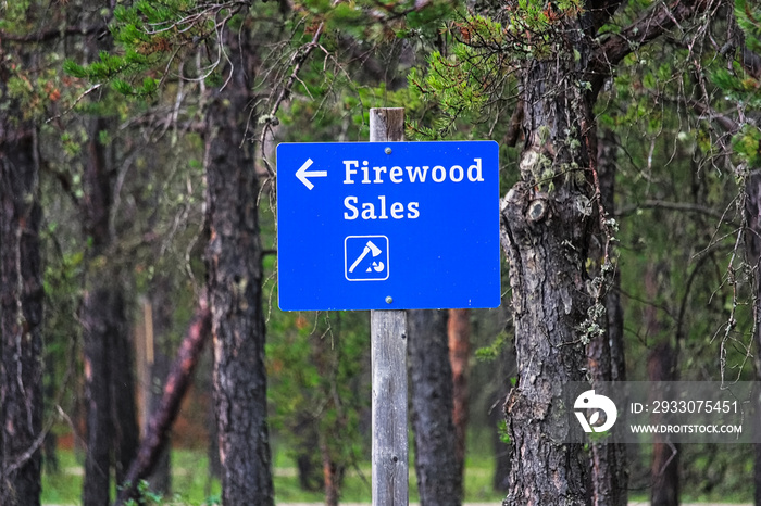 A blue firewood sales sign with a directional arrow