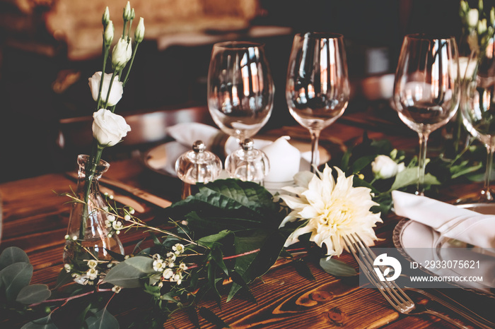 Wedding banquet, serving wooden table with silver plates and decorated with flowers