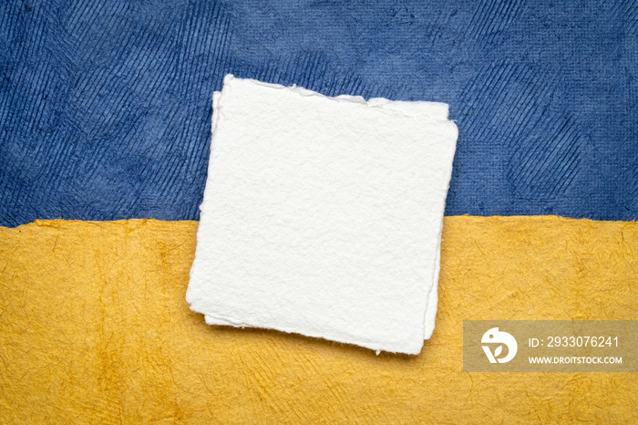 blank sheet of handmade paper against abstract in colors of Ukrainian national flag - blue and yellow