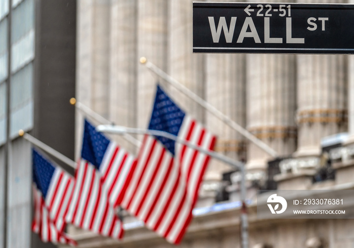 Wall Street  WALL ST  sign and broadway street over American national flags in front of NYSE stock market exchange building background. The New York Stock Exchange locate in economy district