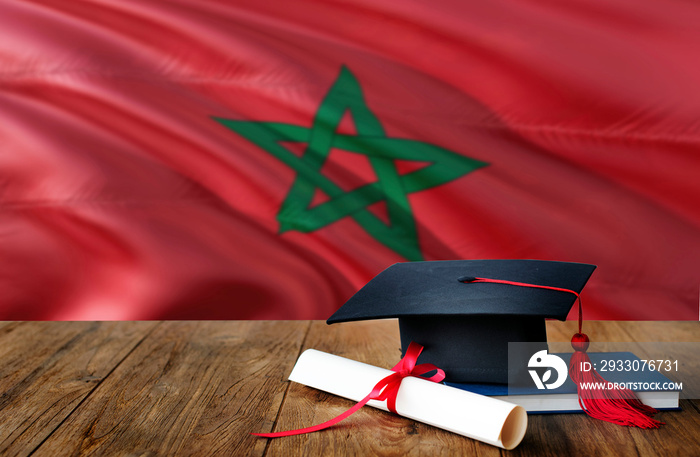 Morocco education concept. Graduation cap and diploma on wooden table, national flag background. Succesful student.