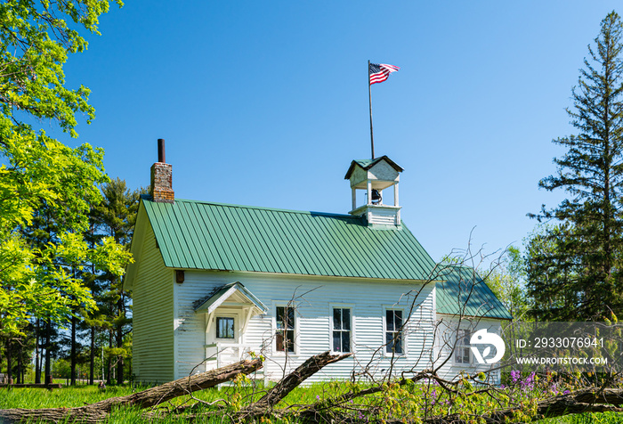 1900’s one room school house with American flag and bell tower in rural Minnesota.